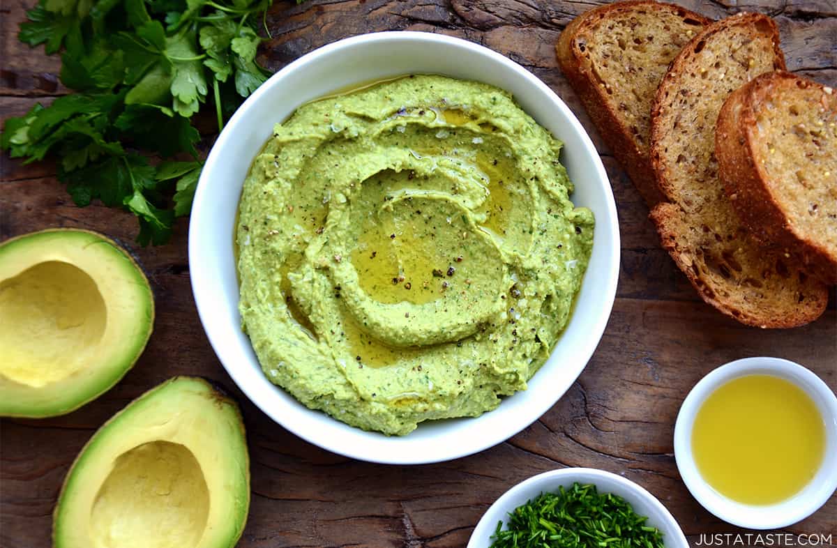 Avocado hummus in a bowl topped with olive oil, flakey salt and pepper.