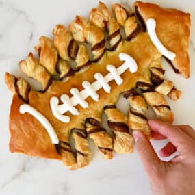 Puff pastry twisted and baked in the shape of a football with vanilla frosting laces.