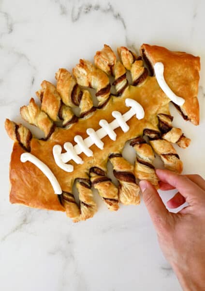 Puff pastry twisted and baked in the shape of a football with vanilla frosting laces.