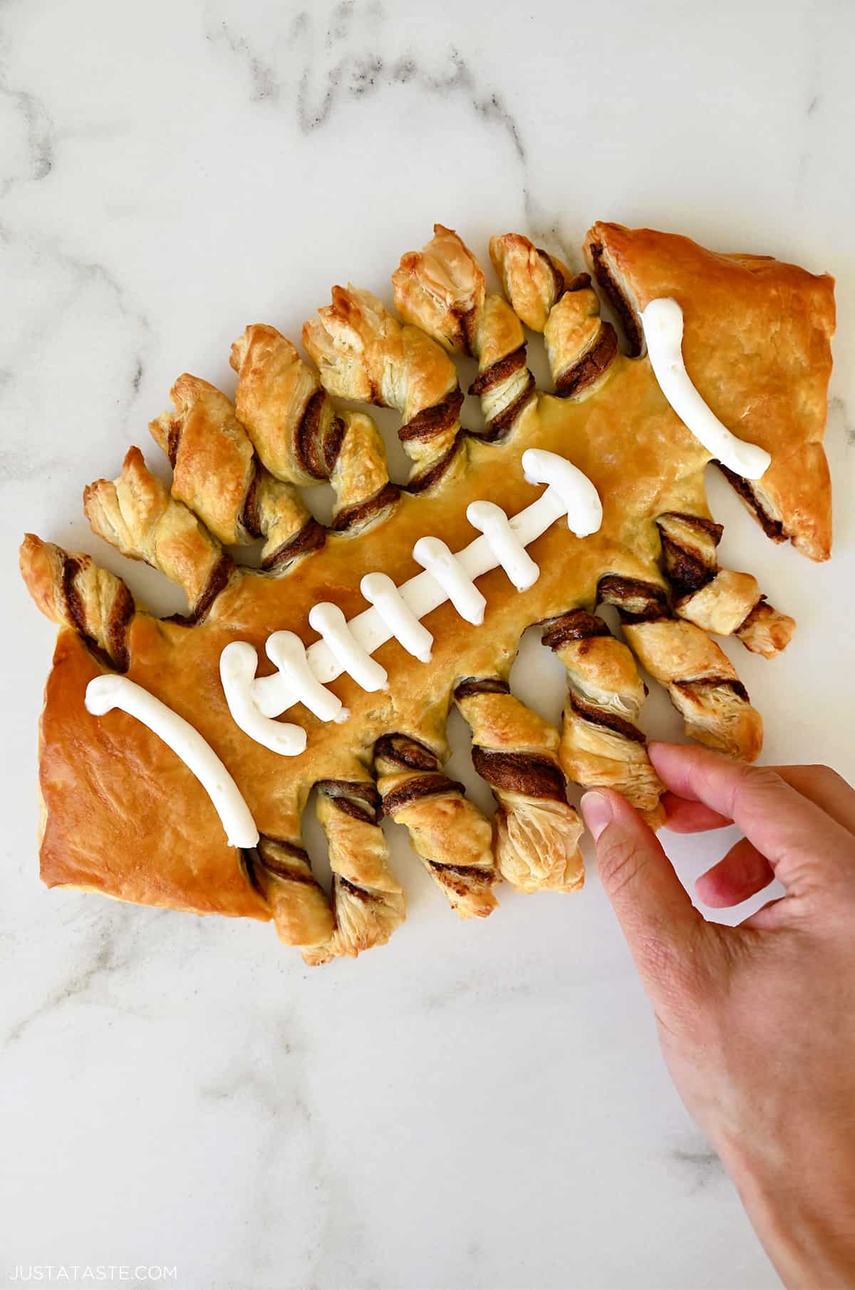 Puff pastry twisted and baked in the shape of a football with vanilla frosting laces.