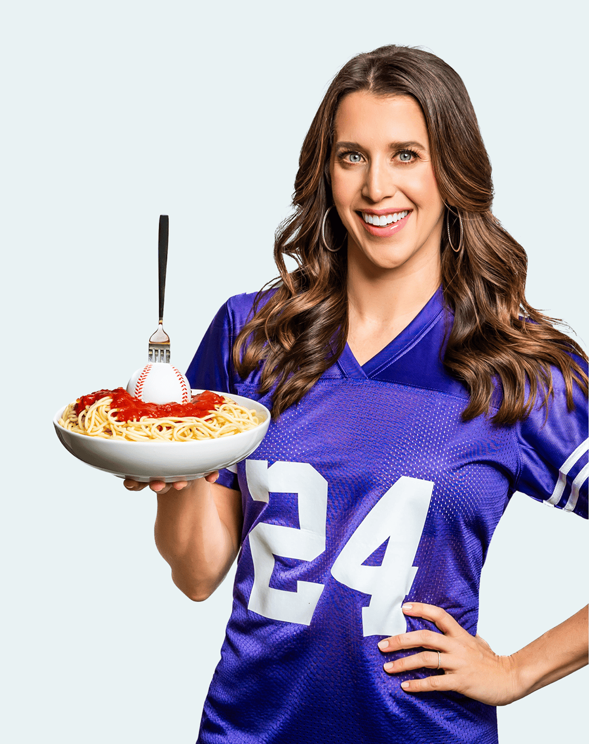 Kelly Senyei in a purple football jersey holding a bowl of past with a baseball in it