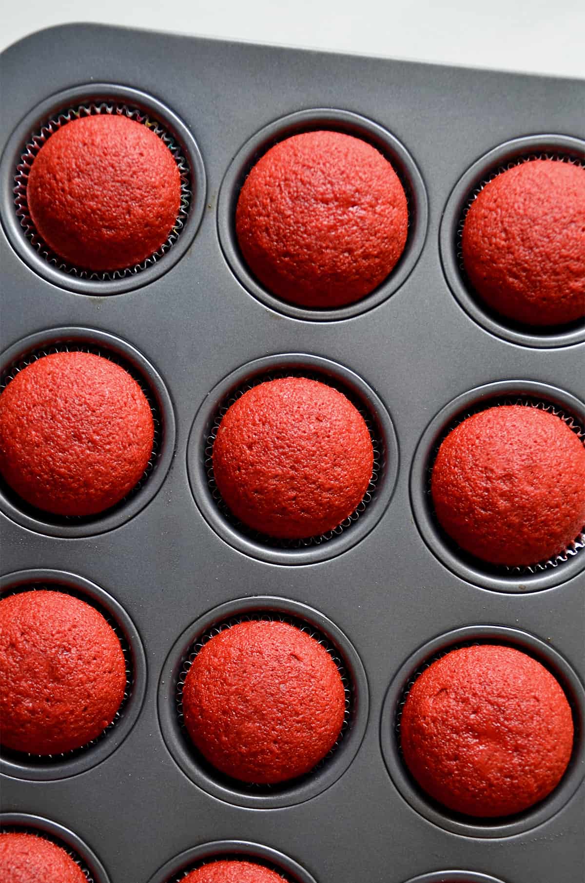 Baked red velvet cupcakes are in a cupcake pan.