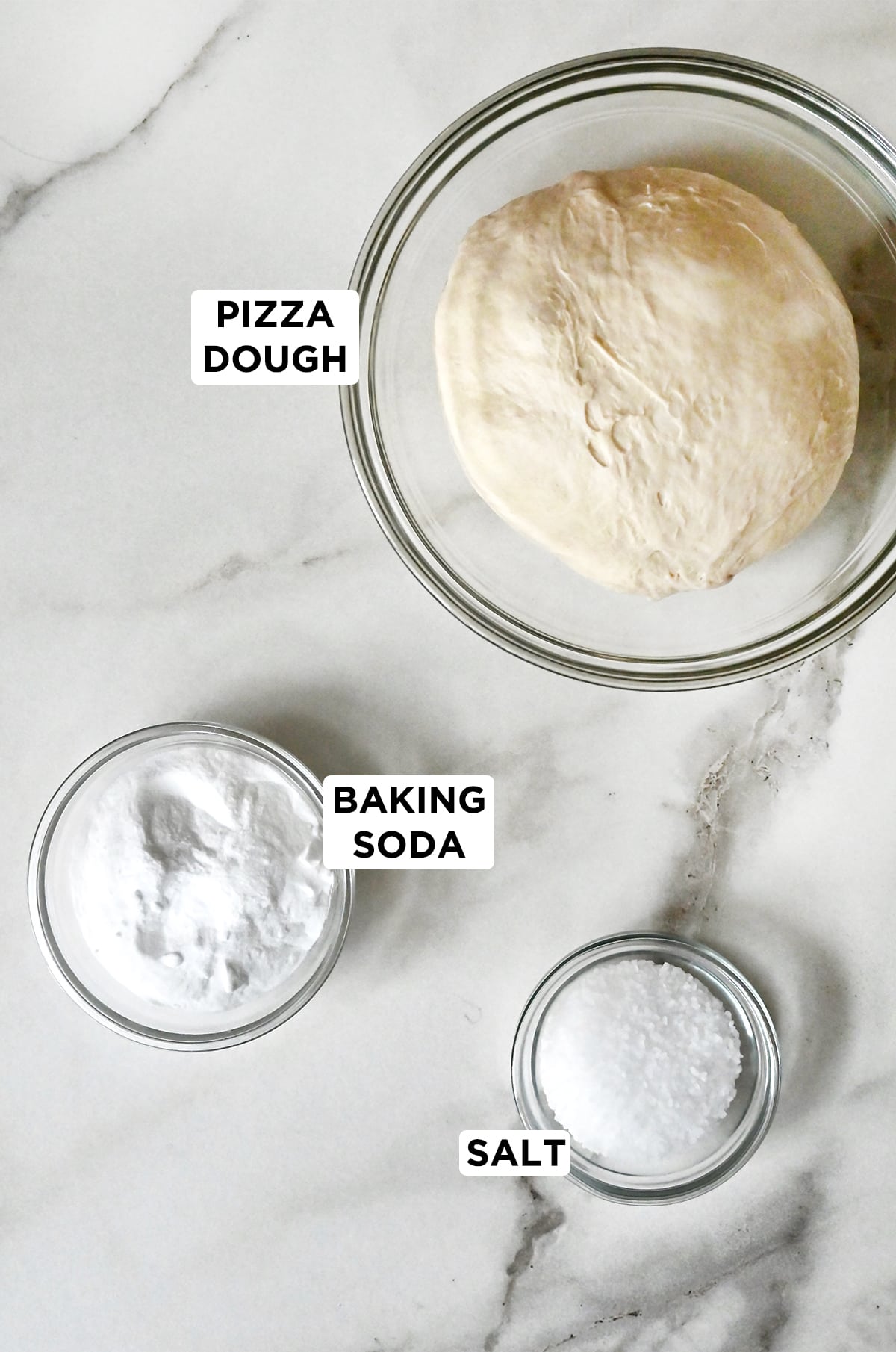 Three glass bowls containing pizza dough, baking soda and salt.