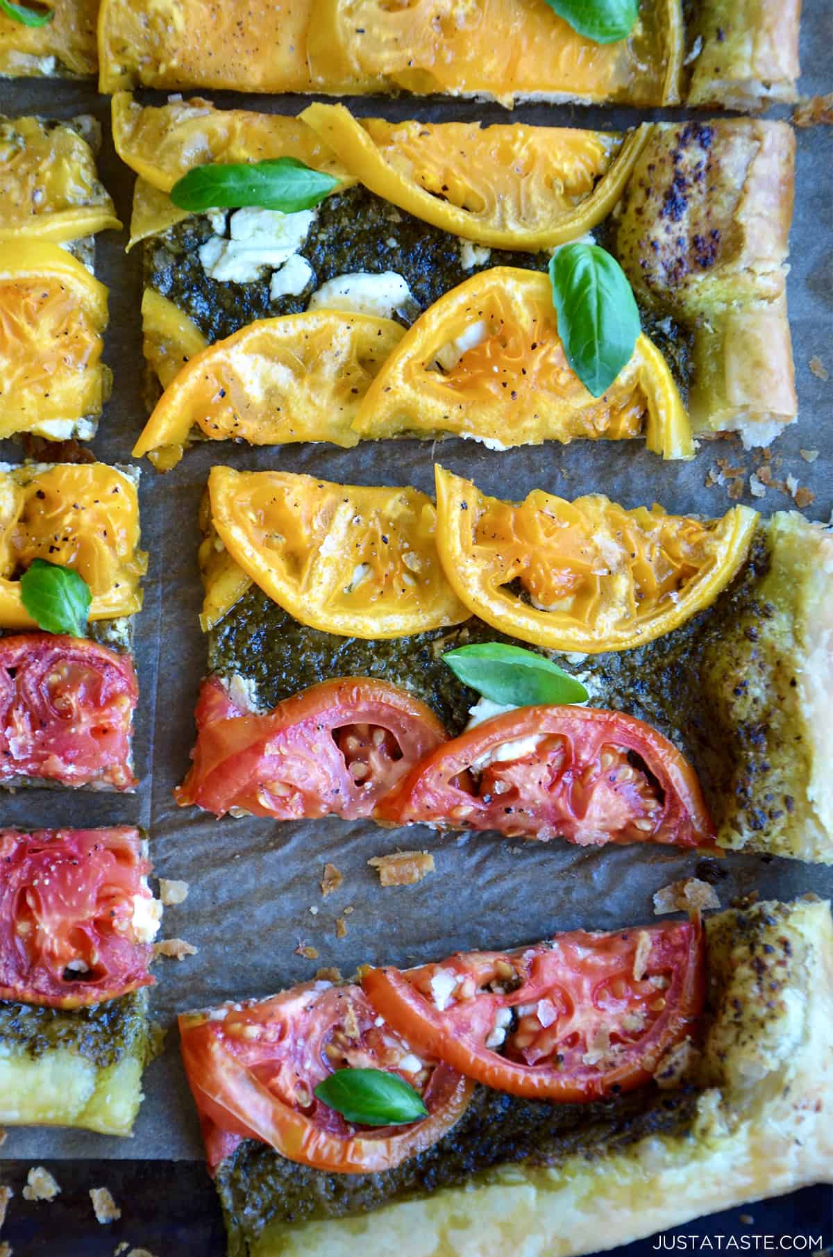 A sliced tomato and goat cheese tart topped with basil.