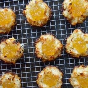 Coconut macaroons filled with pineapple jam are arranged in rows on a cooling rack.