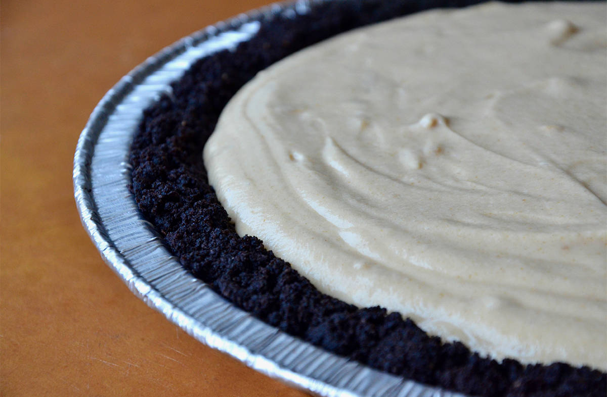 A chocolate cookie pie crust in an aluminum pie tin filled with peanut butter cream.