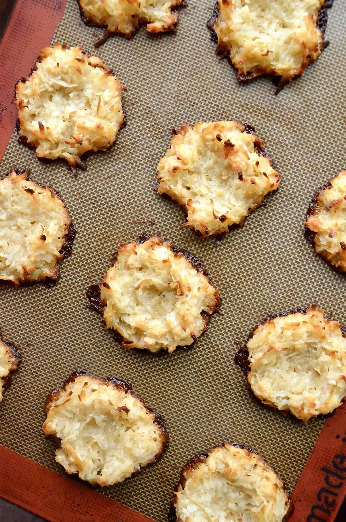 Baked coconut macaroon nests cool on a Silpat baking sheet.