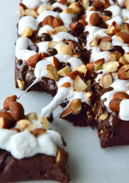 Rock road brownies topped with chopped almonds. A piece of brownie is pulled off the corner.