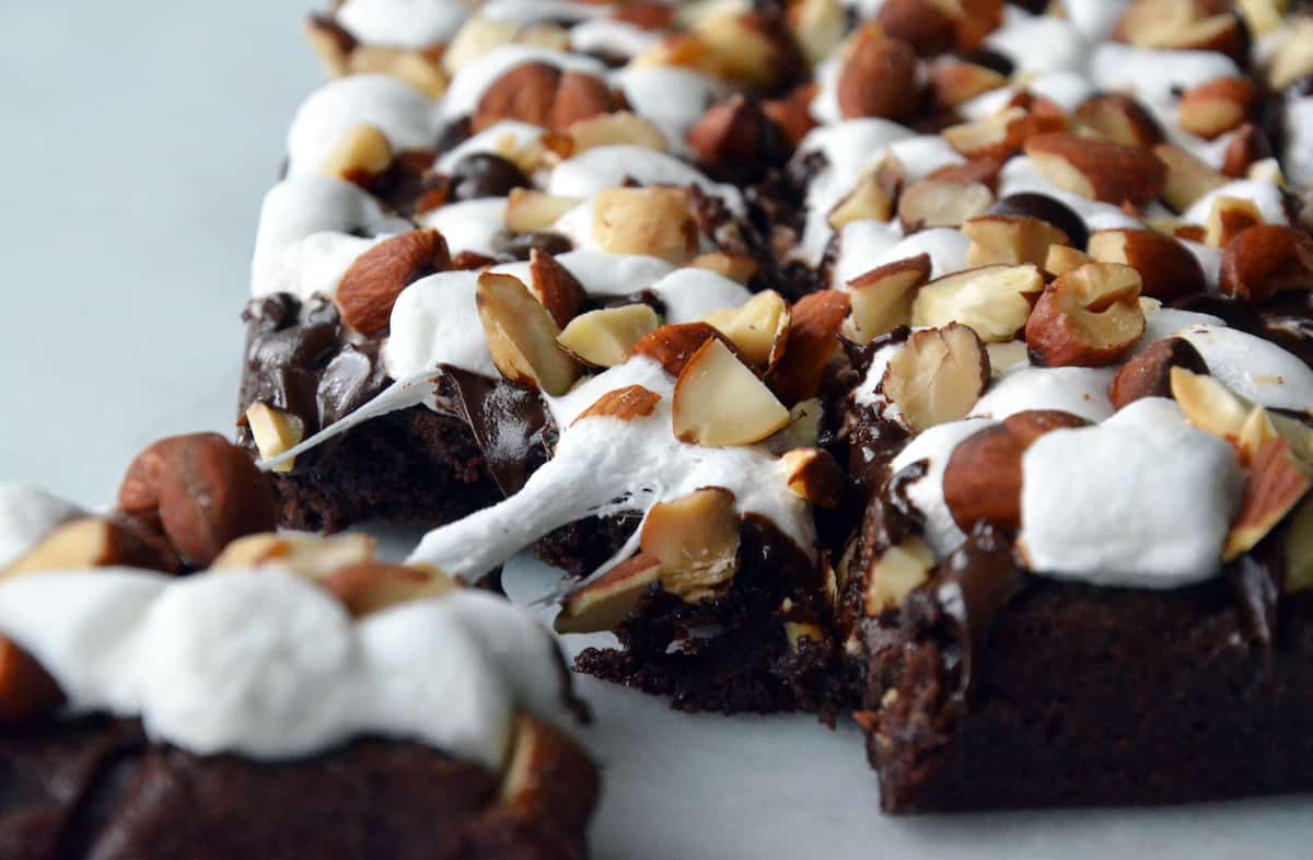 Rocky road brownies topped with chopped almonds. A corner of the brownies is pulled off.