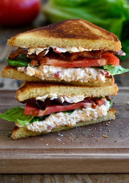 Two halves of a white bread pimento cheese BLT sandwich stacked atop each other.