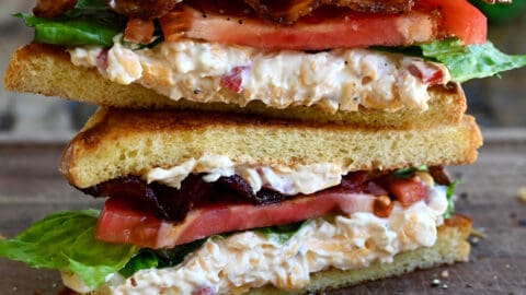 Two halves of a white bread pimento cheese BLT sandwich stacked atop each other.