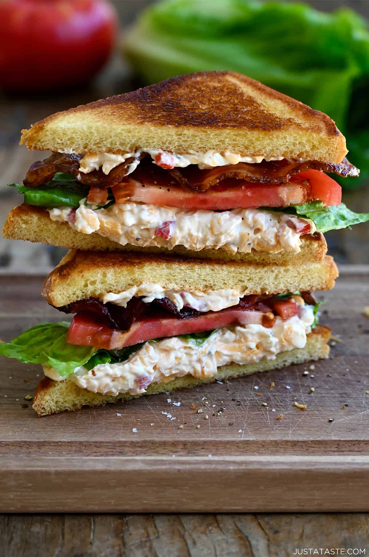 Two halves of a white bread pimento cheese BLT sandwich stacked atop each other. 