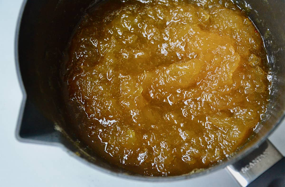 A saucepan with a spout is filled with pineapple jam.