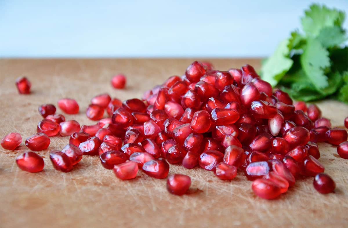 A pile of pomegranate seeds on a cutting board.