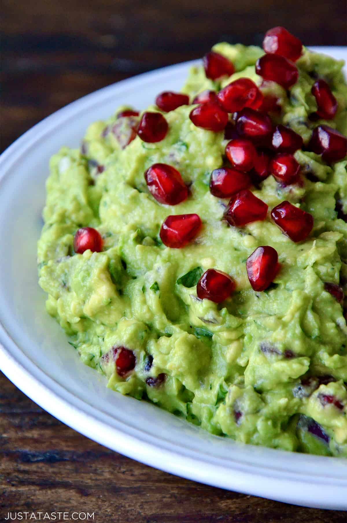 A bowl of pomegranate guacamole topped with more pomegranate seeds.