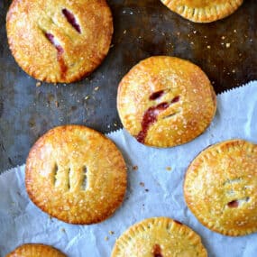 Baked hand pies filled with strawberries and Nutella sit on a piece of parchment paper.