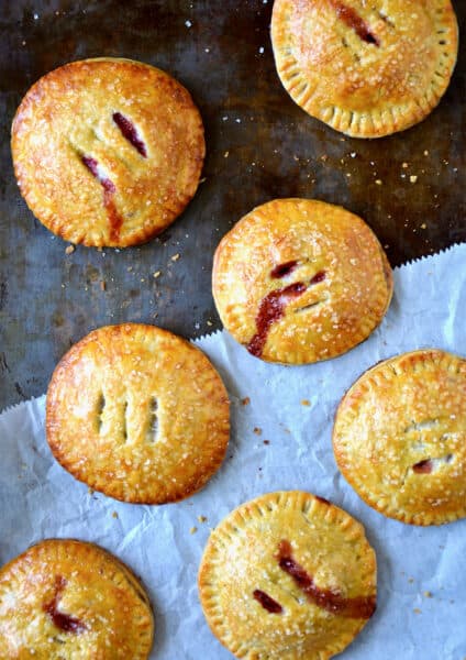 Baked hand pies filled with strawberries and Nutella sit on a piece of parchment paper.