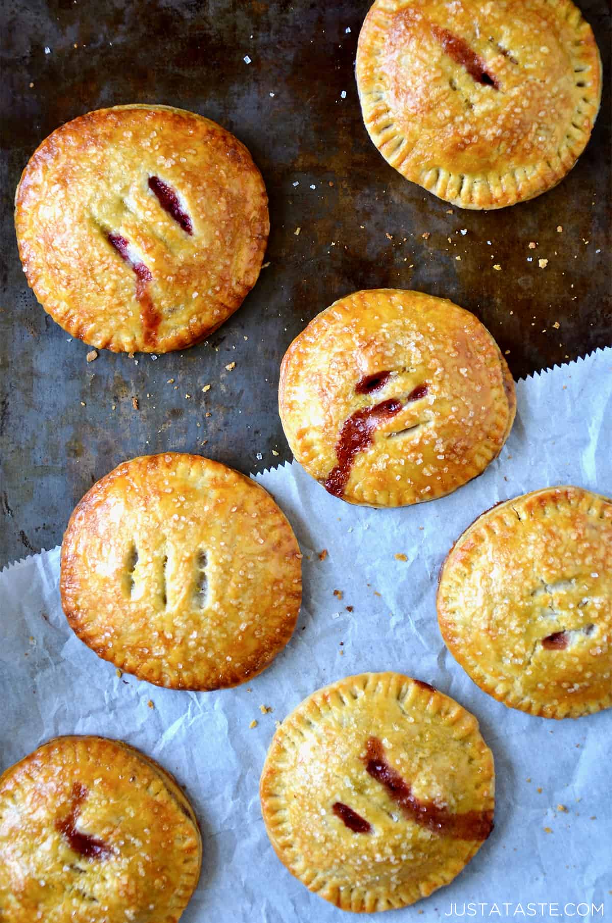 Baked hand pies filled with strawberries and Nutella sit on a piece of parchment paper.