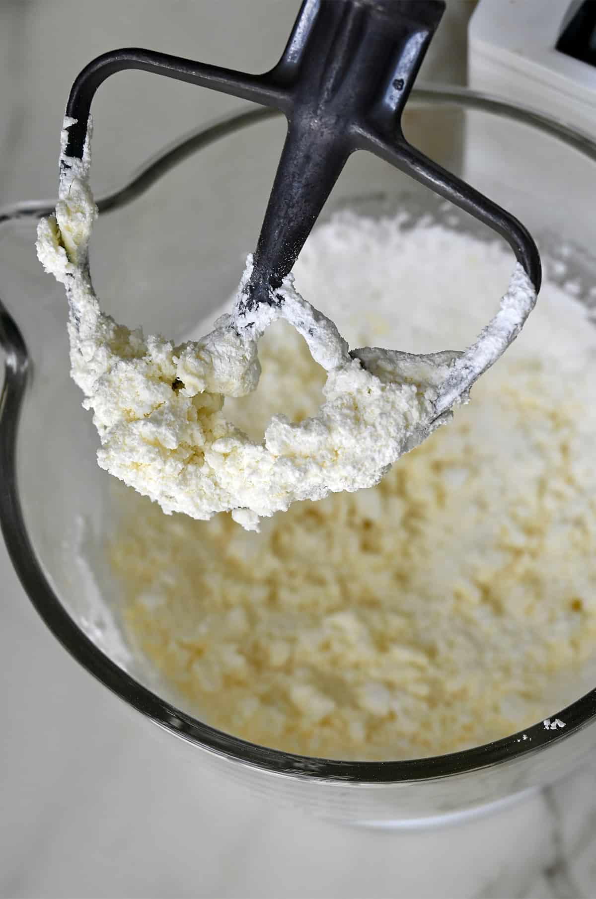 Powdered sugar mixed with salt and butter in the bowl of a hand mixer with the paddle attachment.