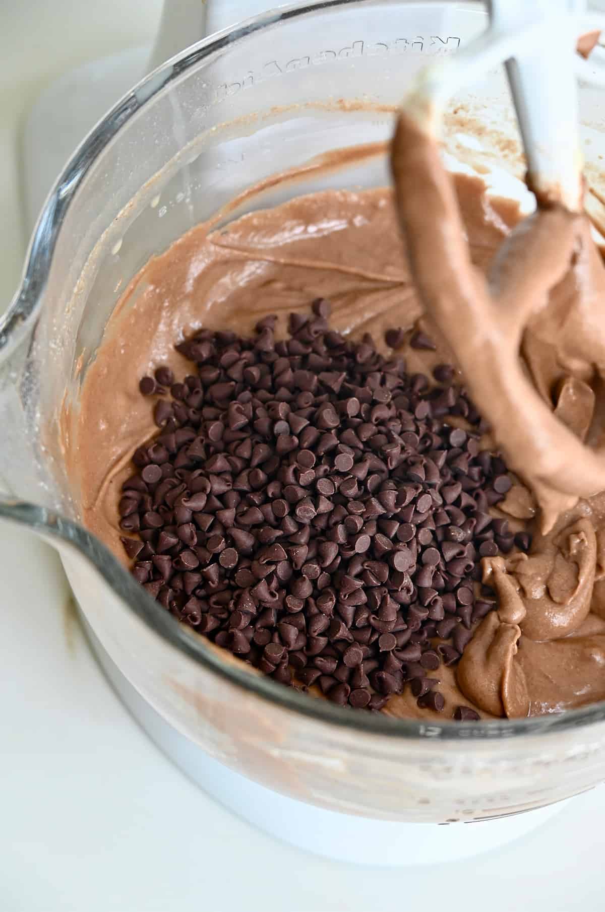 Mini chocolate chips and chocolate cake batter in a bowl of a stand mixer. 