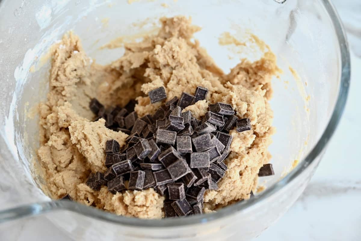 Cookie dough topped with chocolate chunks in a glass bowl.