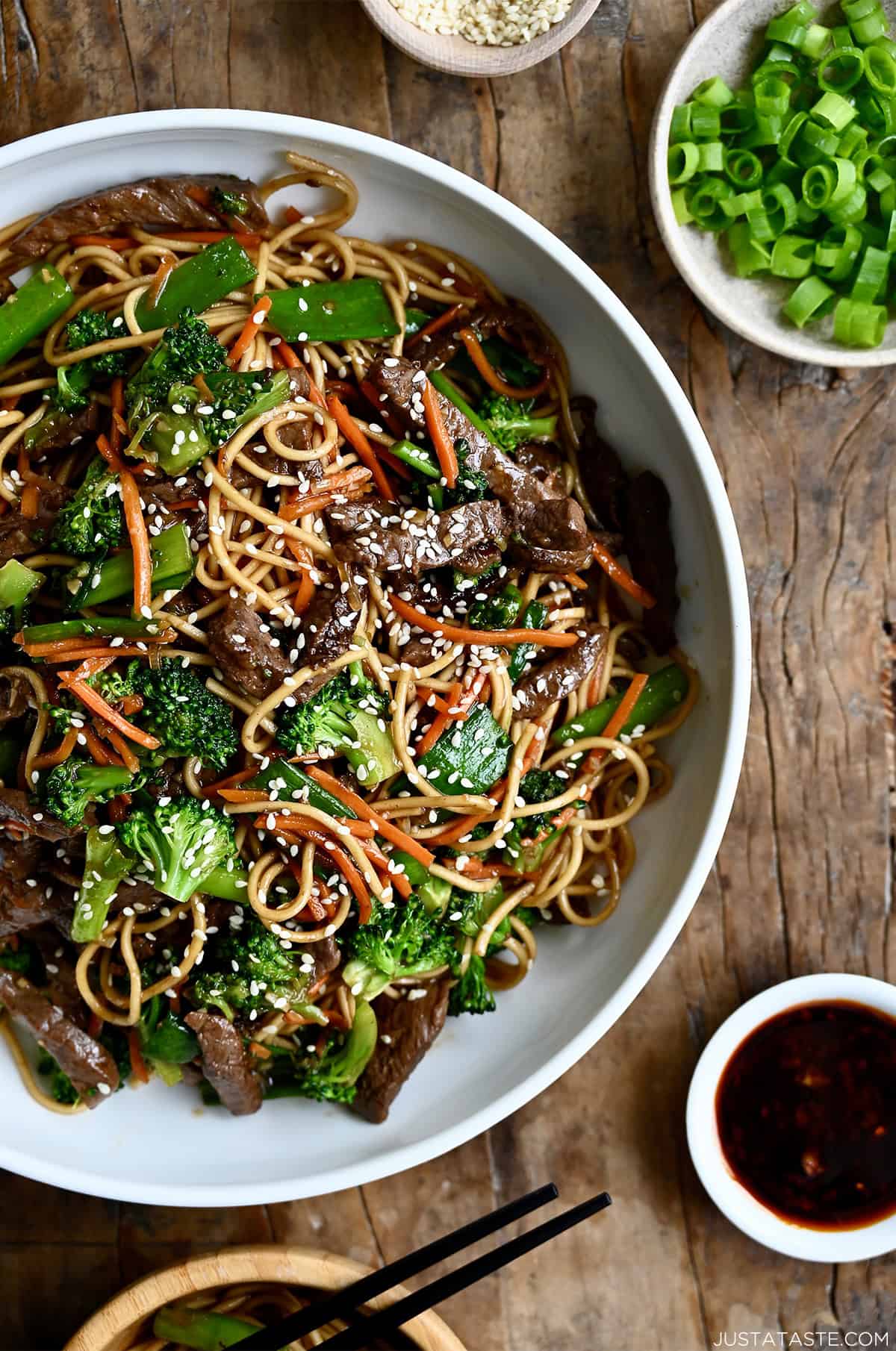 Beef lo Mein with broccoli, snap peas and shredded carrots in a white bowl.