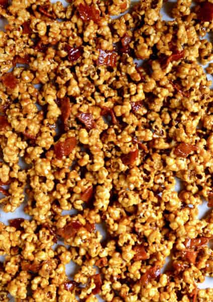 Caramel popcorn with bacon on a parchment-lined baking sheet.