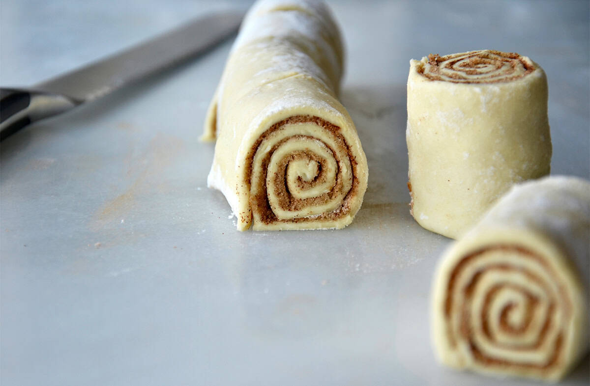 A log of cinnamon roll dough with a couple of pieces cut off.