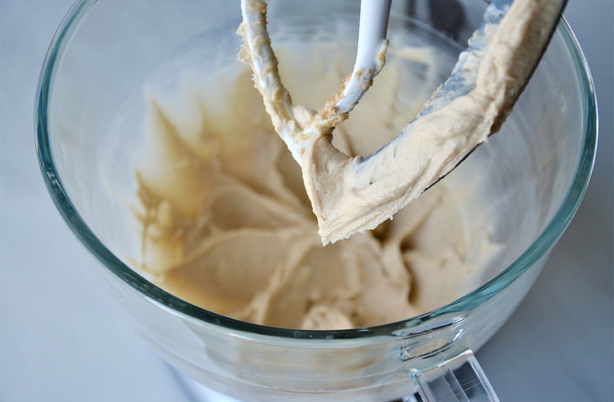 Sticky bun batter in a large glass stand mixer mixing bowl. The stand mixer is fitted with the paddle attachment.
