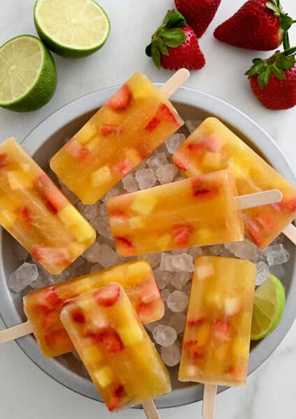 Peach sangria popsicles in a bowl with ice.