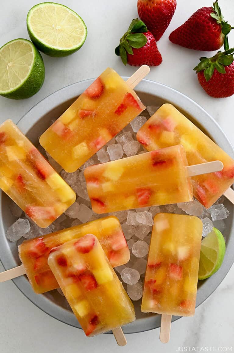 Peach sangria popsicles in a bowl with ice.