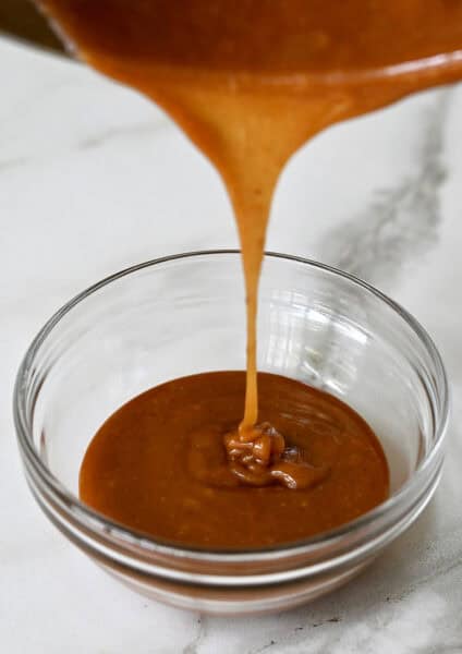 Bourbon caramel sauce being poured into a glass bowl.