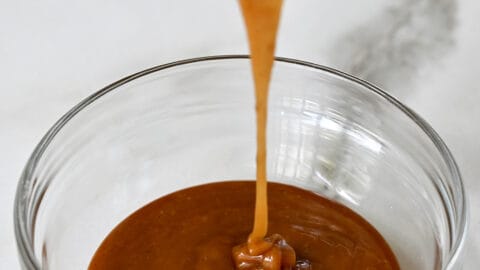 Bourbon caramel sauce being poured into a glass bowl.