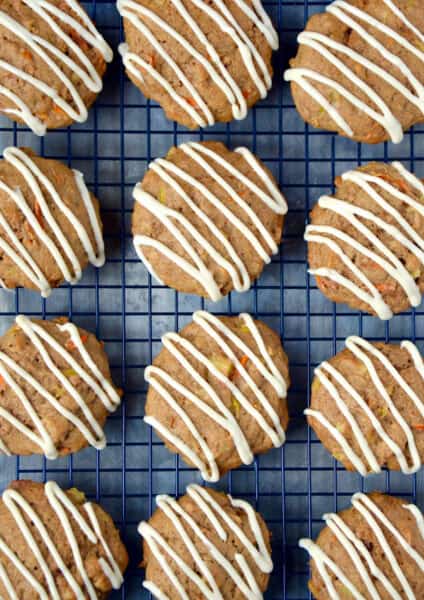 Carrot cake cookies drizzled with icing on a cooling rack.