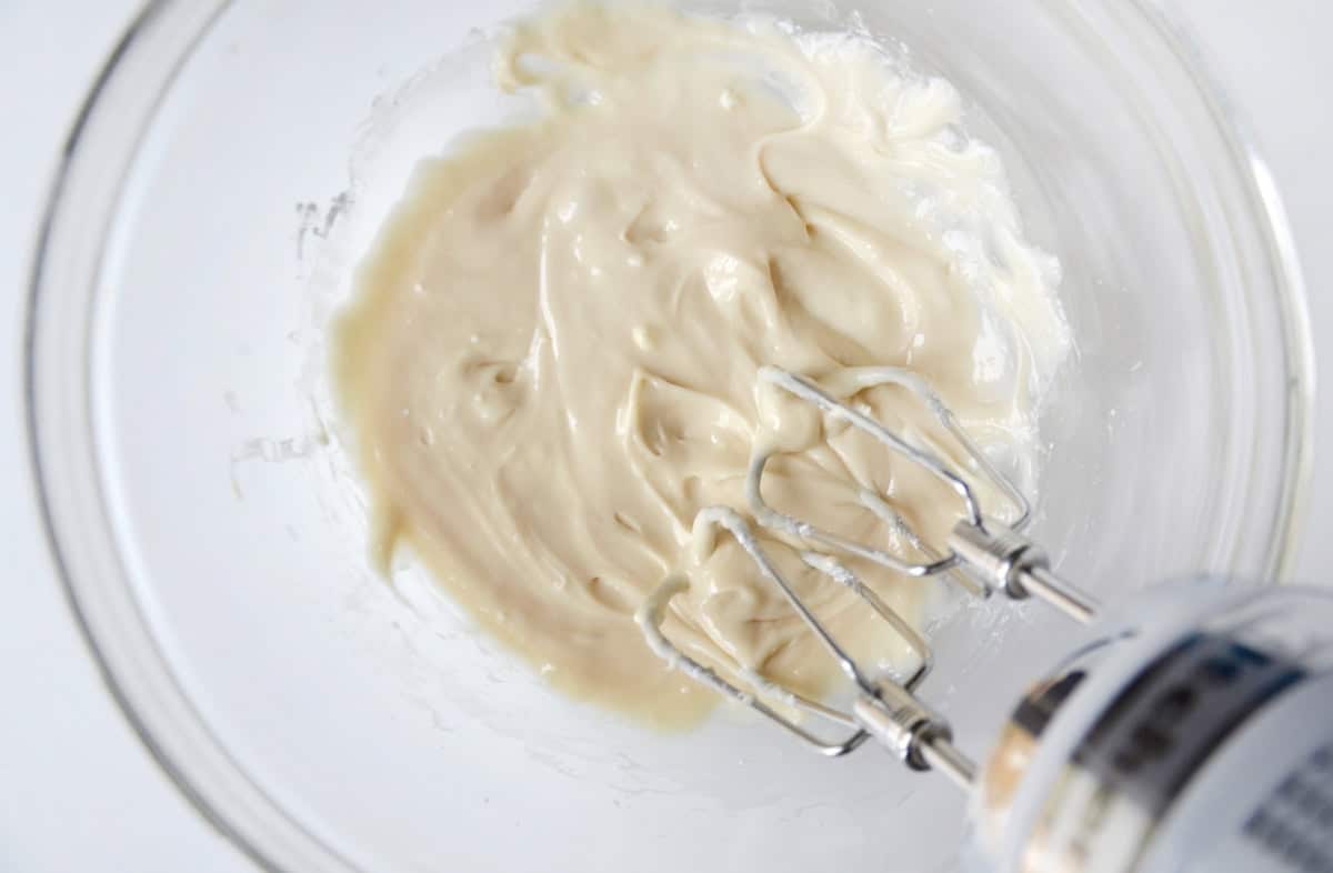 Cream cheese icing in a glass mixing bowl.
