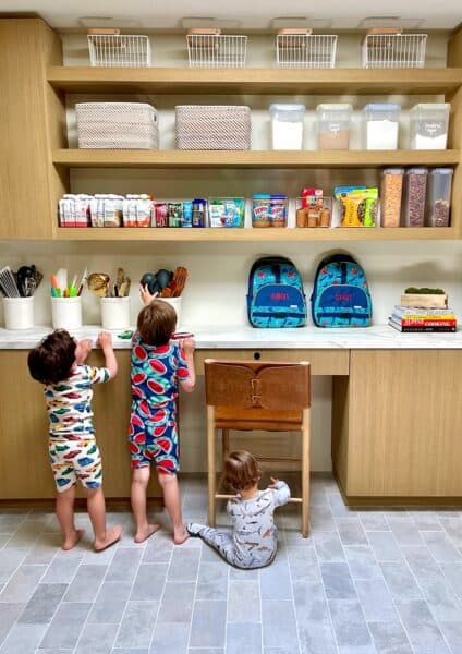 Three kids in a pantry choosing foods to pack into their lunchboxes.