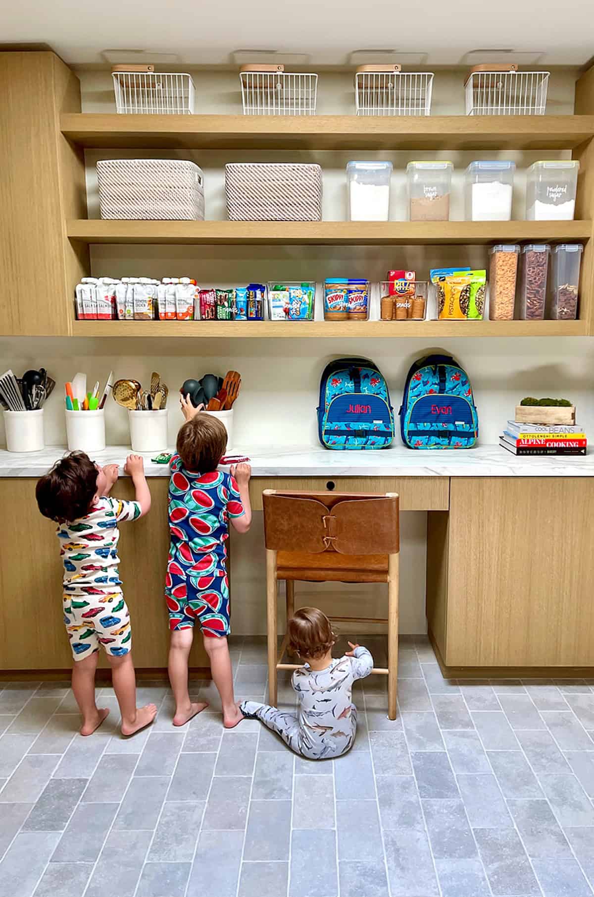 Three kids in a pantry choosing foods to pack into their lunchboxes.