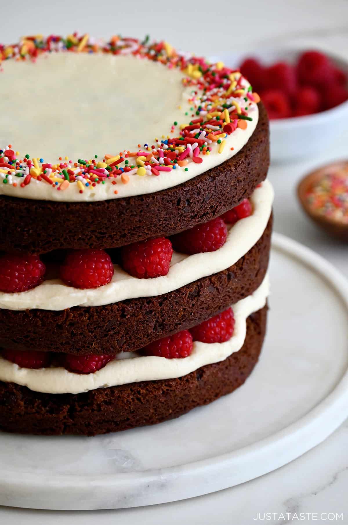 Three tiered chocolate cake with cream cheese frosting and fresh raspberries.