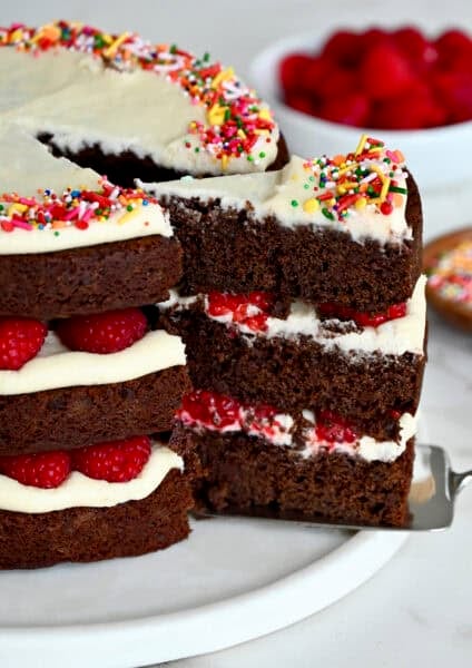 A three-tiered chocolate cake with cream cheese frosting and fresh raspberries.