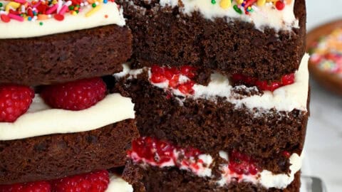 A three-tiered chocolate cake with cream cheese frosting and fresh raspberries.