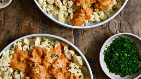 Two plates containing Hungarian chicken paprikas over nokedli.