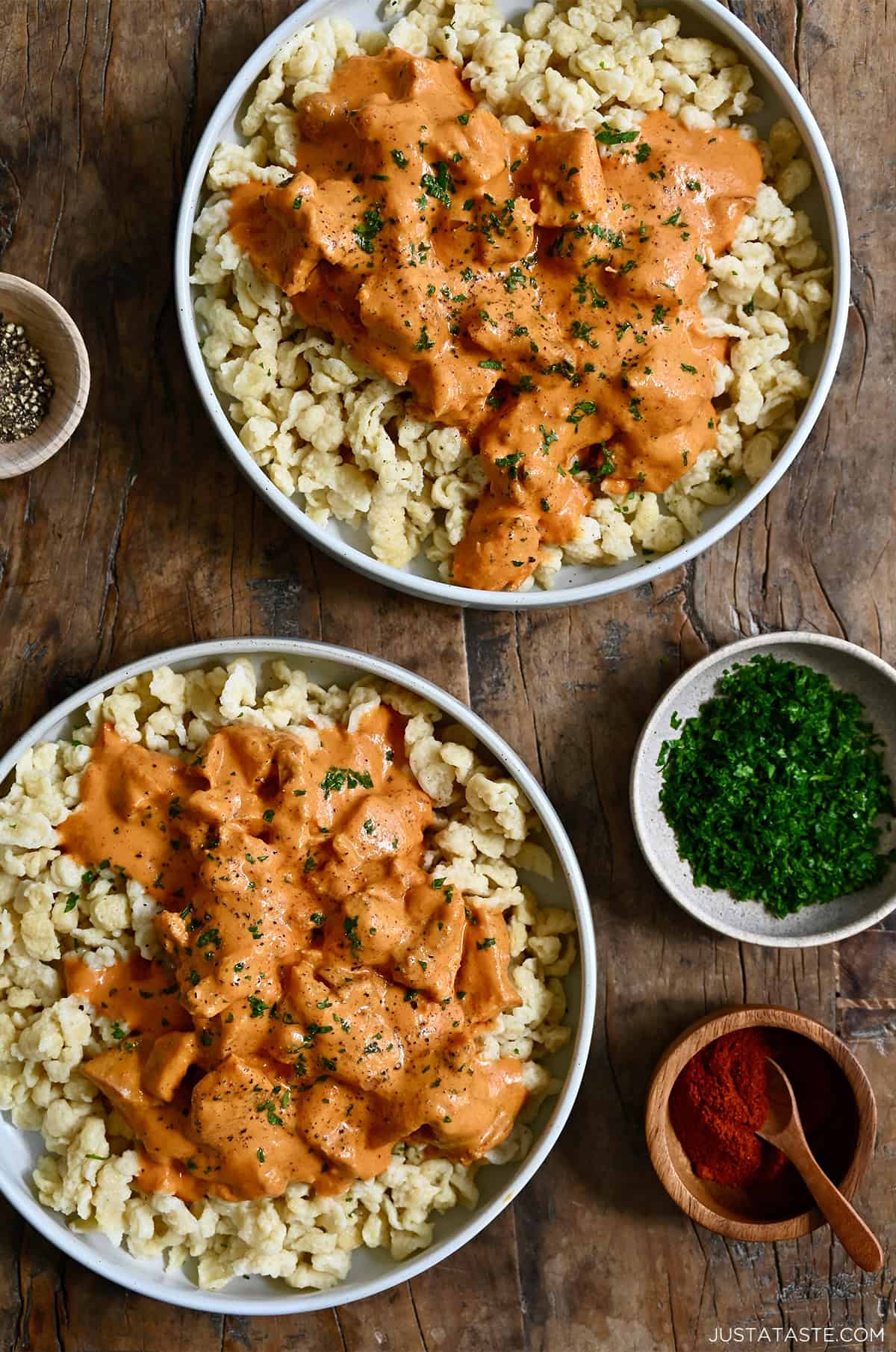 Two plates containing Hungarian chicken paprikas over nokedli.