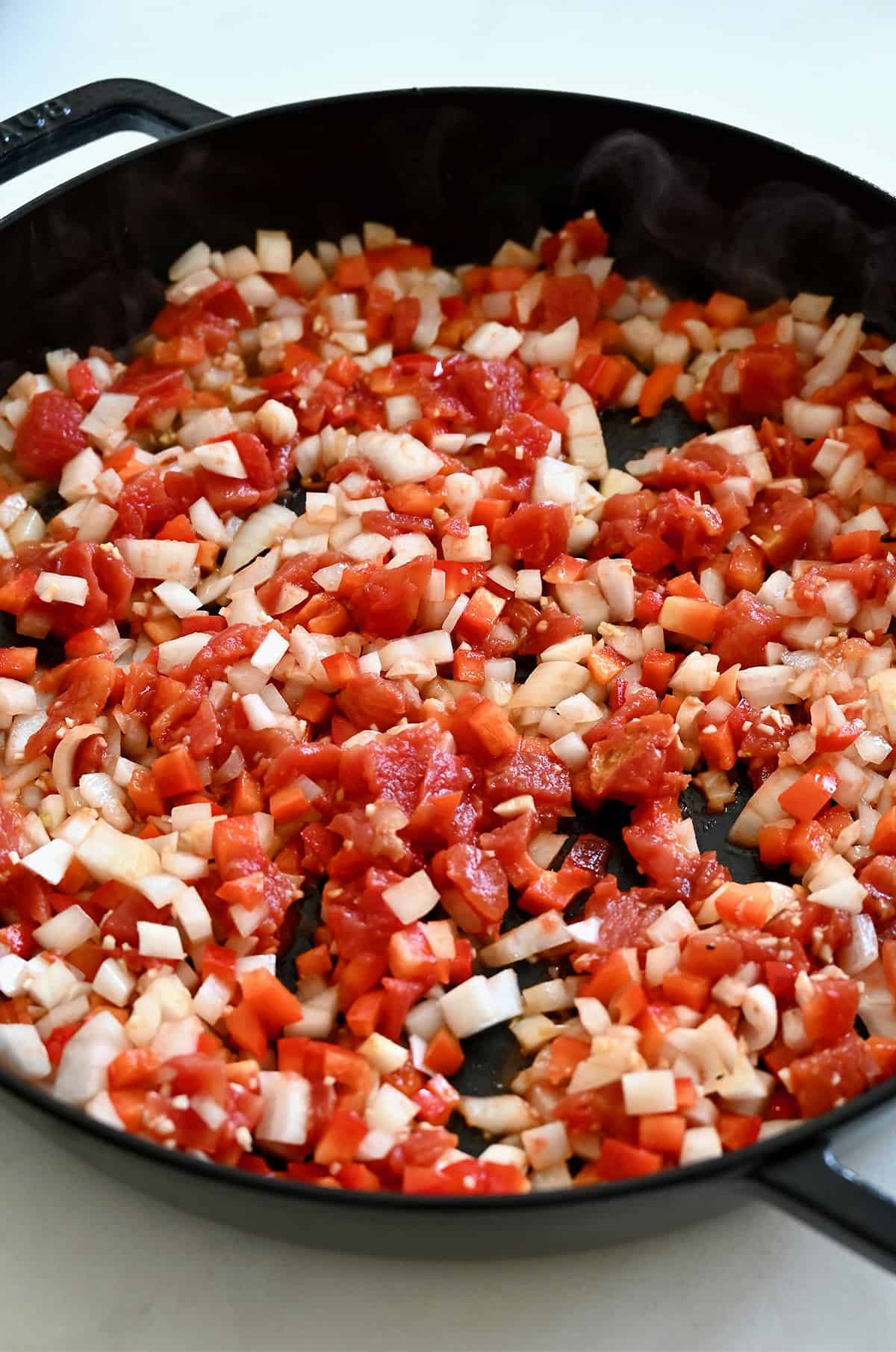 Diced veggies cooking in a large skillet.