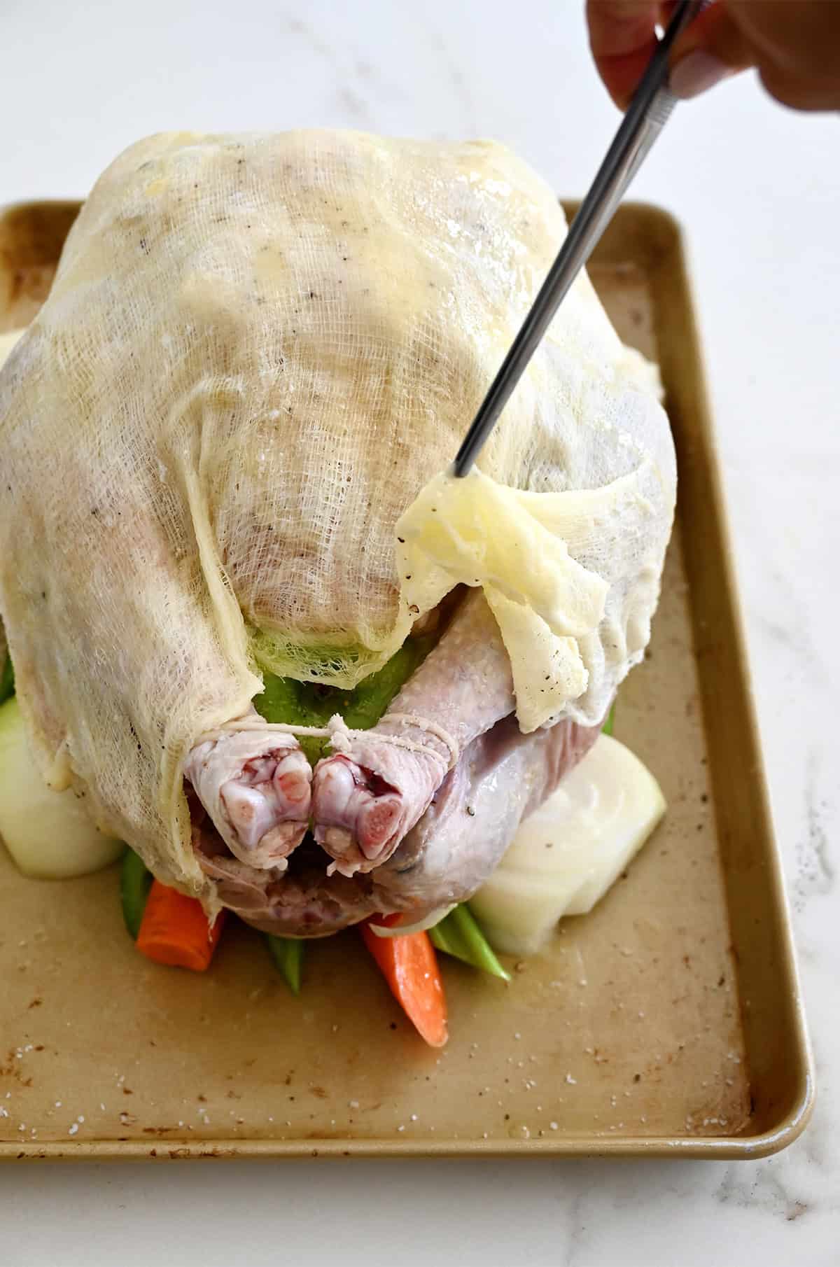 A butter-soaked cheesecloth draped over a turkey before going into the oven to roast.