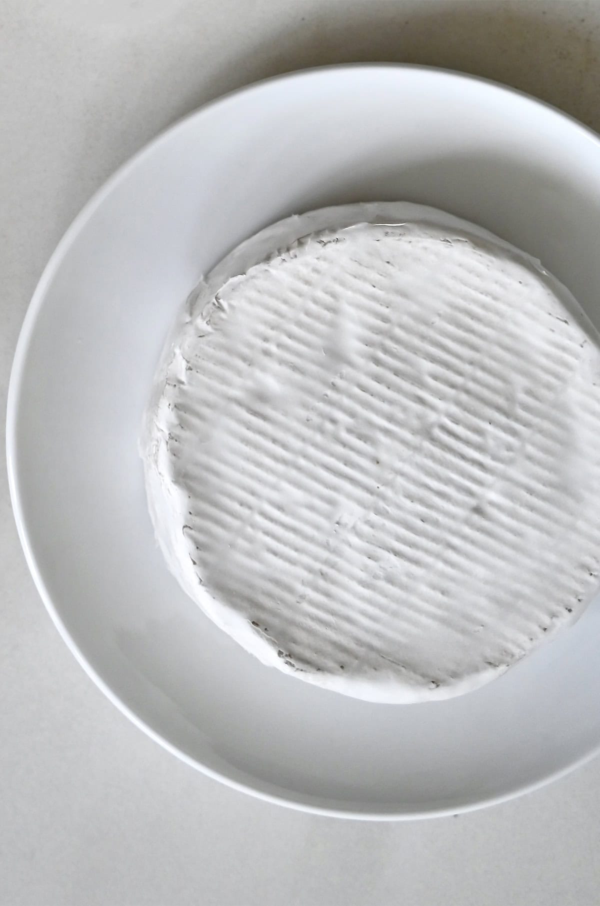 A wheel of Brie cheese on a plate.