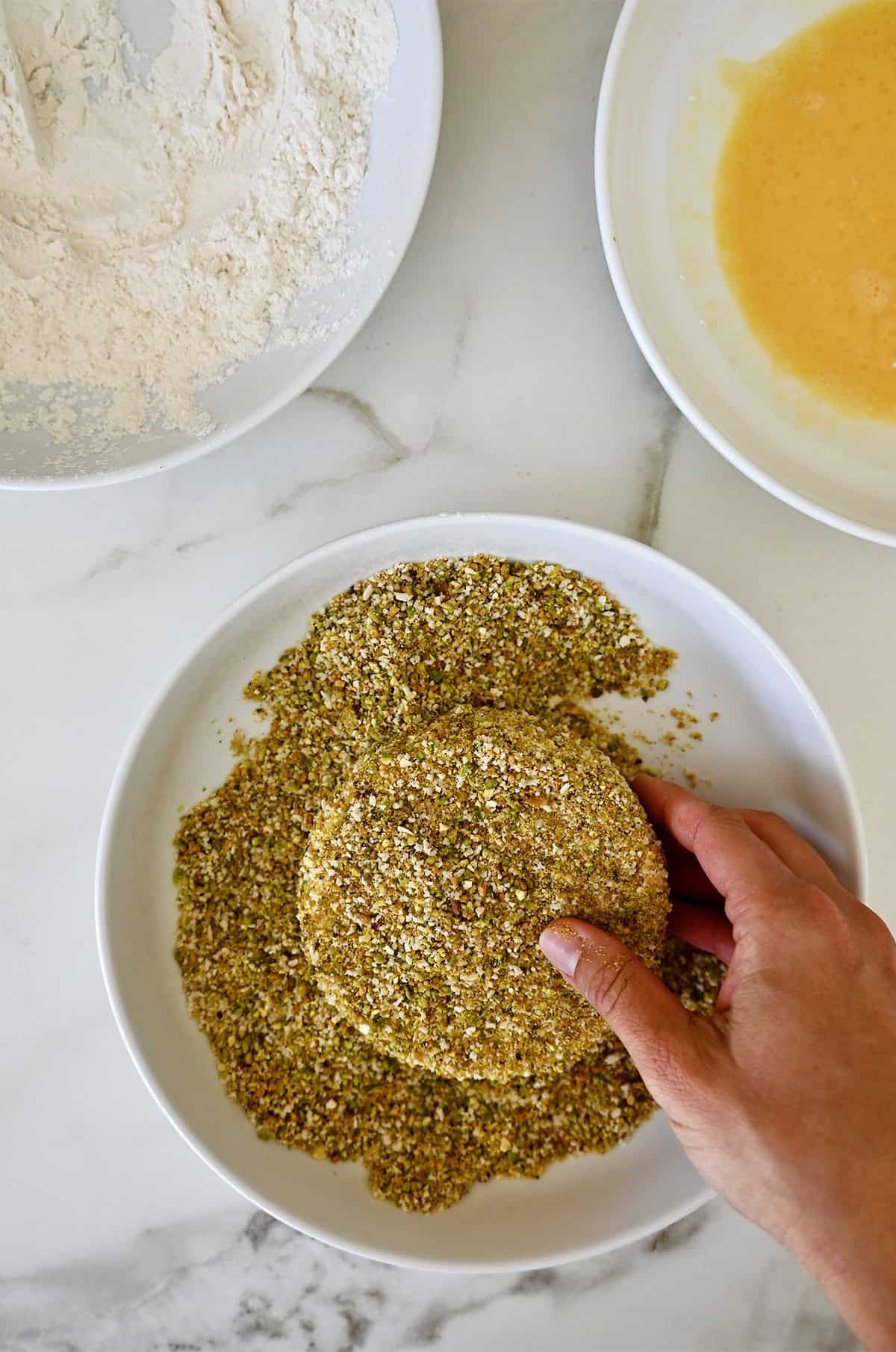 Brie cheese that's been dredged in flour, followed by an egg wash and coated with ground pistachios.