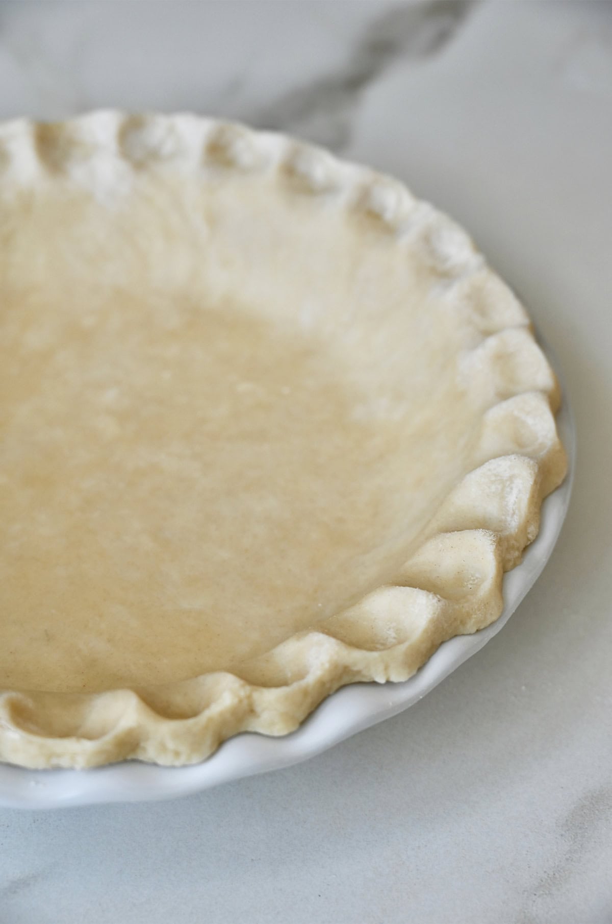 Crimped pie crust in a white pie plate.
