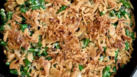 Creamy green bean casserole topped with French's crispy fried onions in a cast iron skillet.