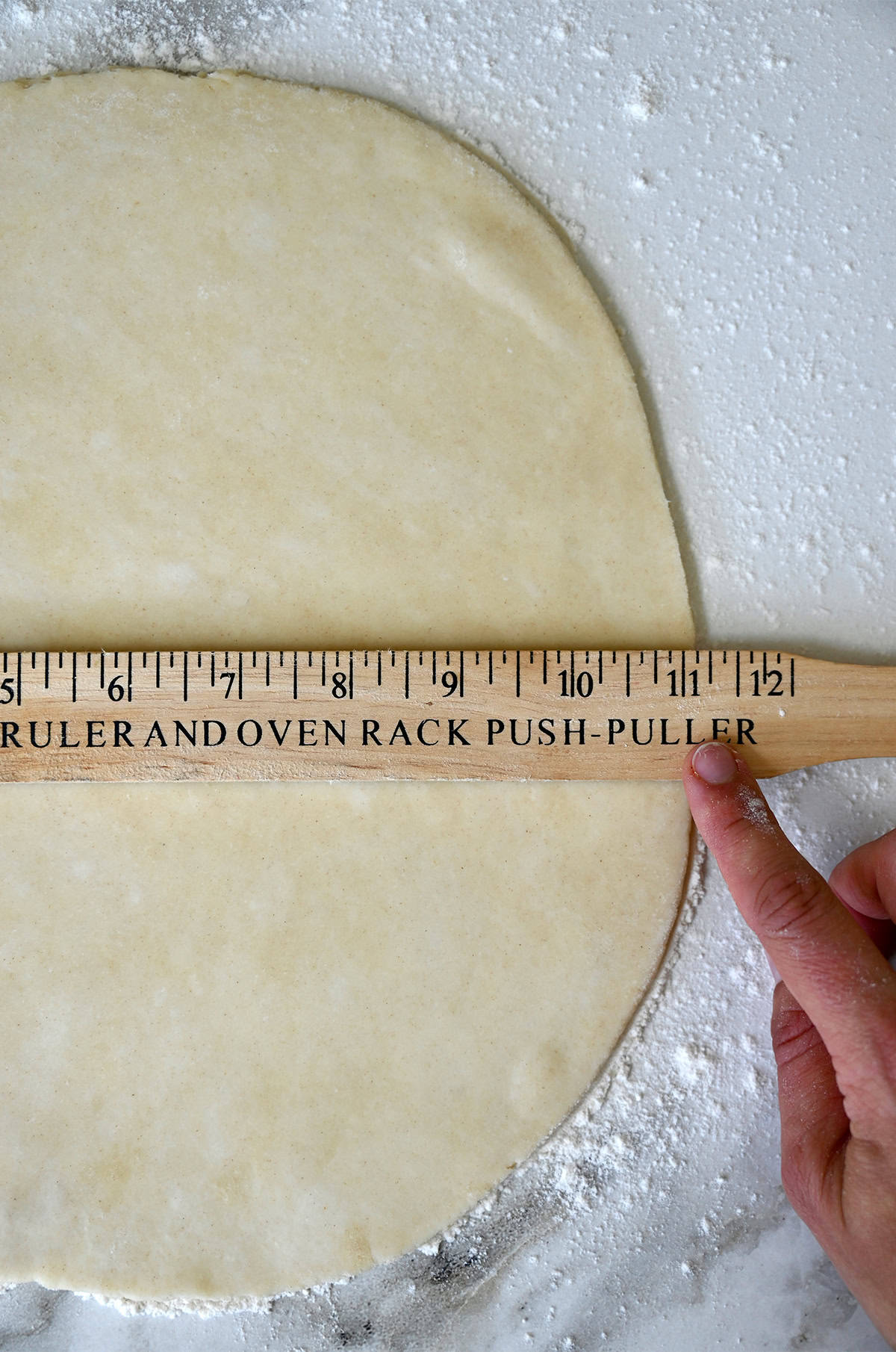 Measuring rolled out pie dough with a ruler.