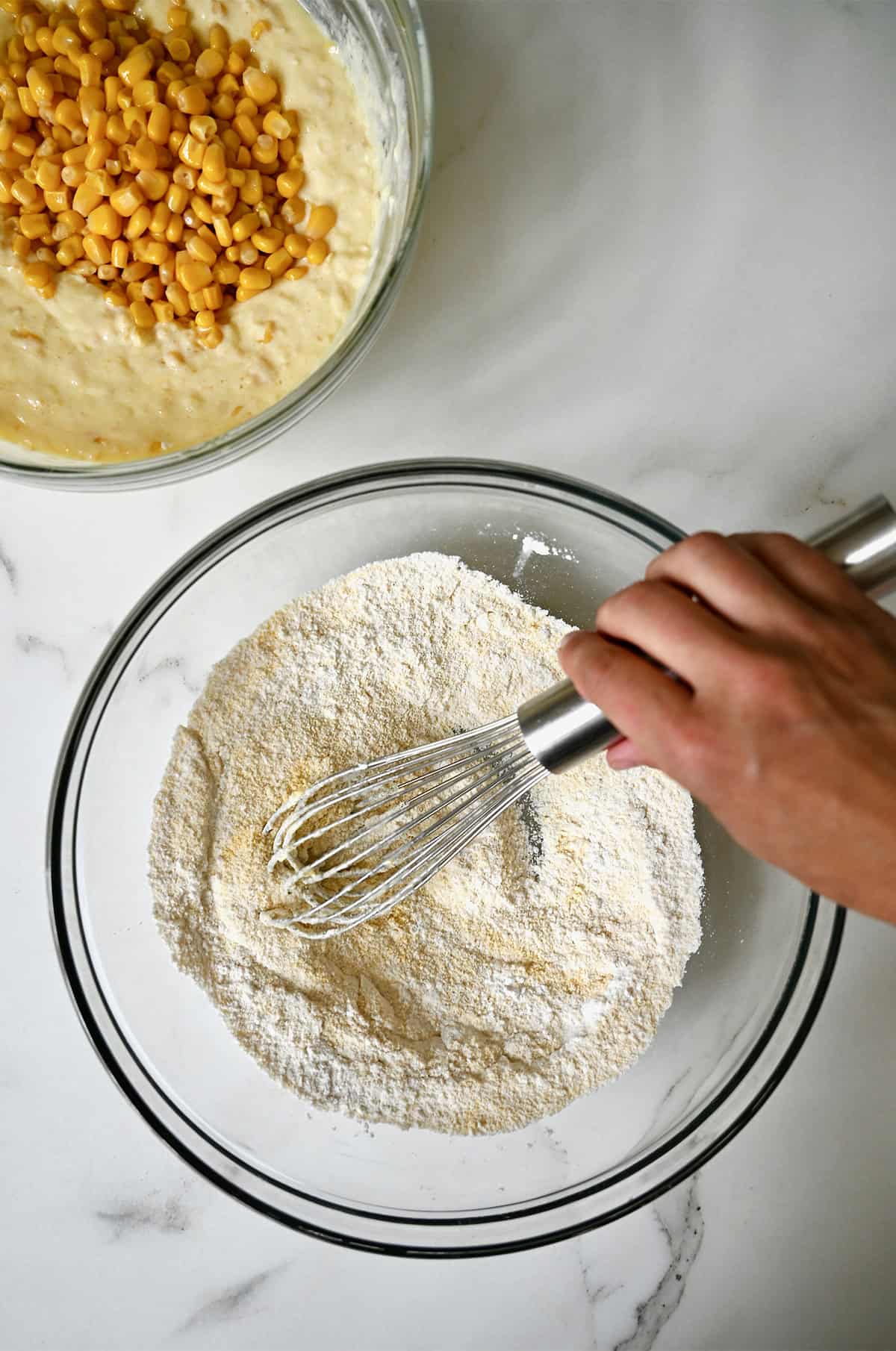 Two bowls containing dry and wet ingredients for homemade corn casserole.